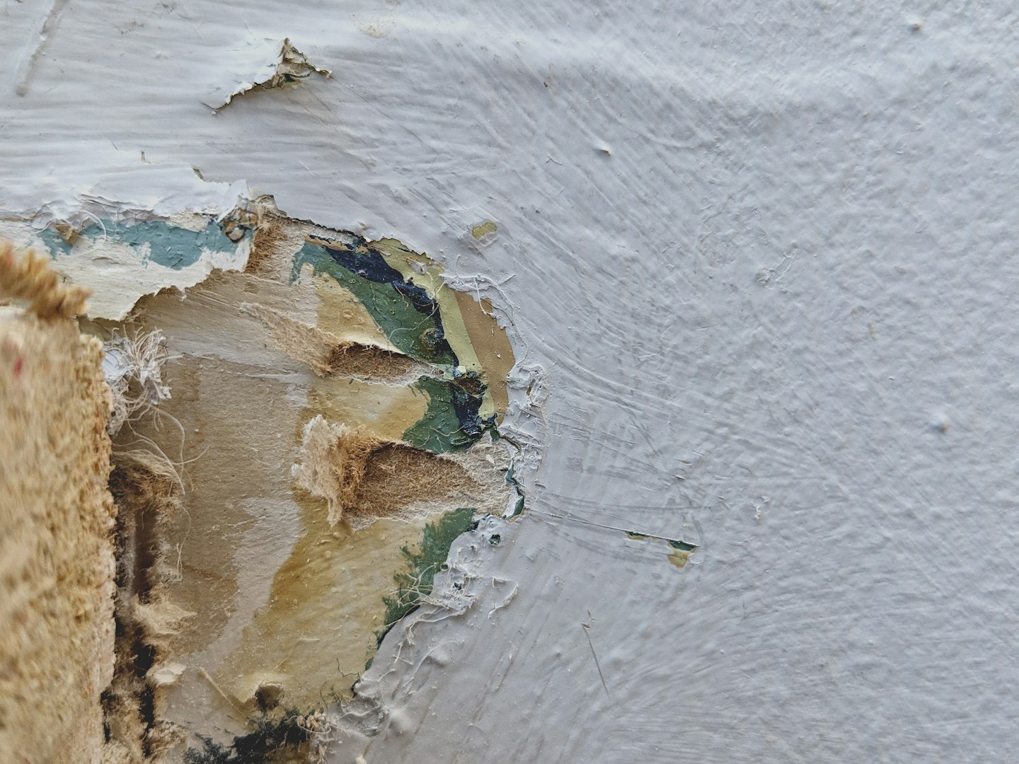 A mature Caucasian man in uniform squats and writes a note on a piece of paper on the floor before replacing an old window frame with a new one in a bedroom on a sunny spring day. Vertical side view, medium shot. Concept: repair and replacement of windows and window frames, using technology, mathematical calculations.