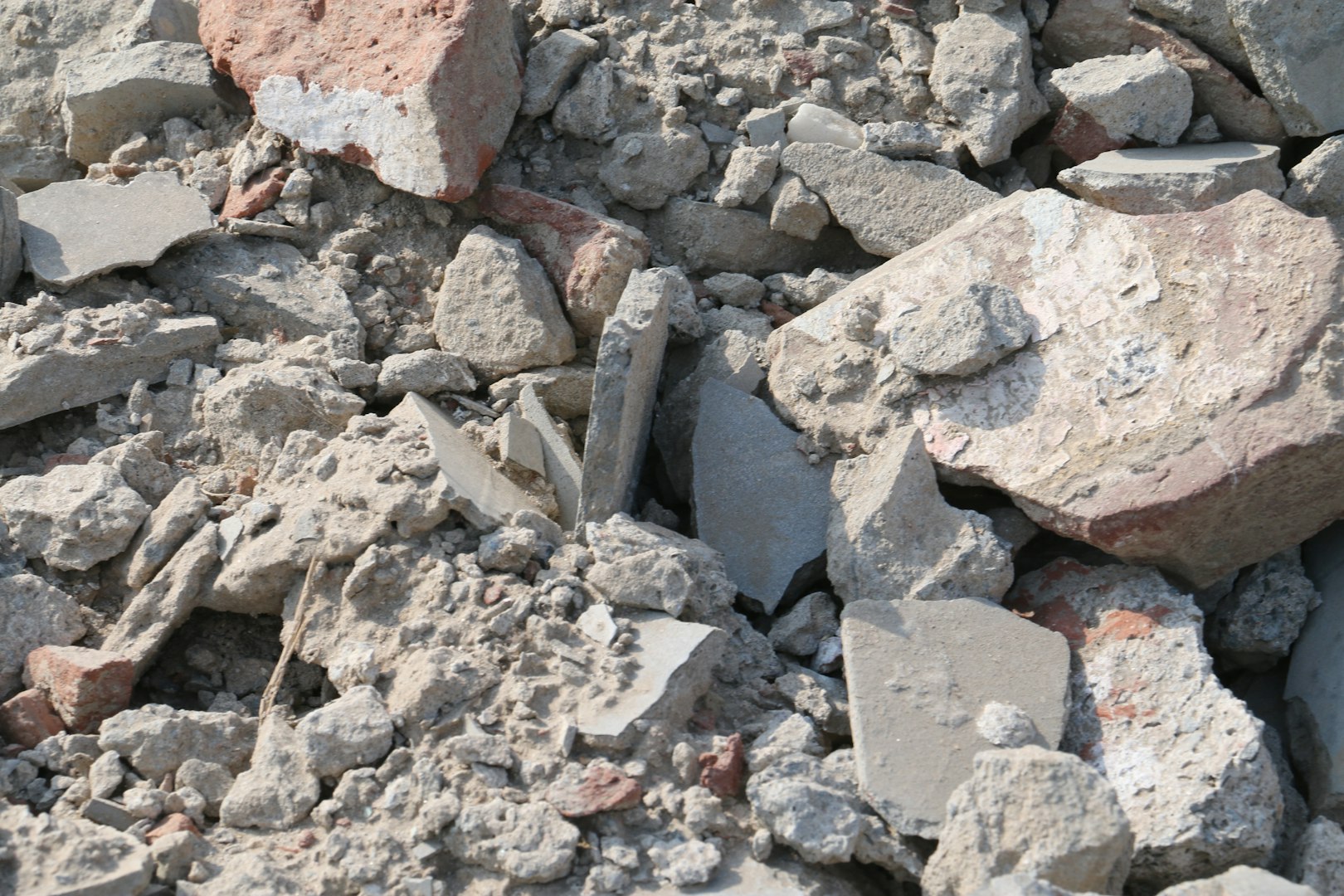 A mature Caucasian man in uniform squats and writes a note on a piece of paper on the floor before replacing an old window frame with a new one in a bedroom on a sunny spring day. Vertical side view, medium shot. Concept: repair and replacement of windows and window frames, using technology, mathematical calculations.